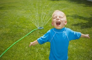 kid playing in sprinkler