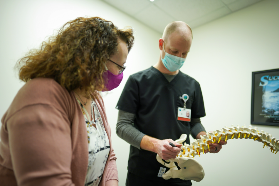 Doctor showing patient where her pain is coming from on fake spinal cord